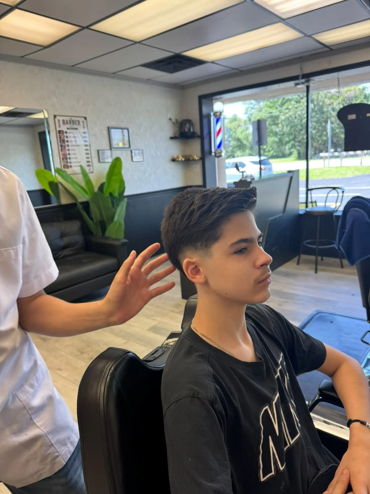 Barber styling a kid haircut with caution and smile